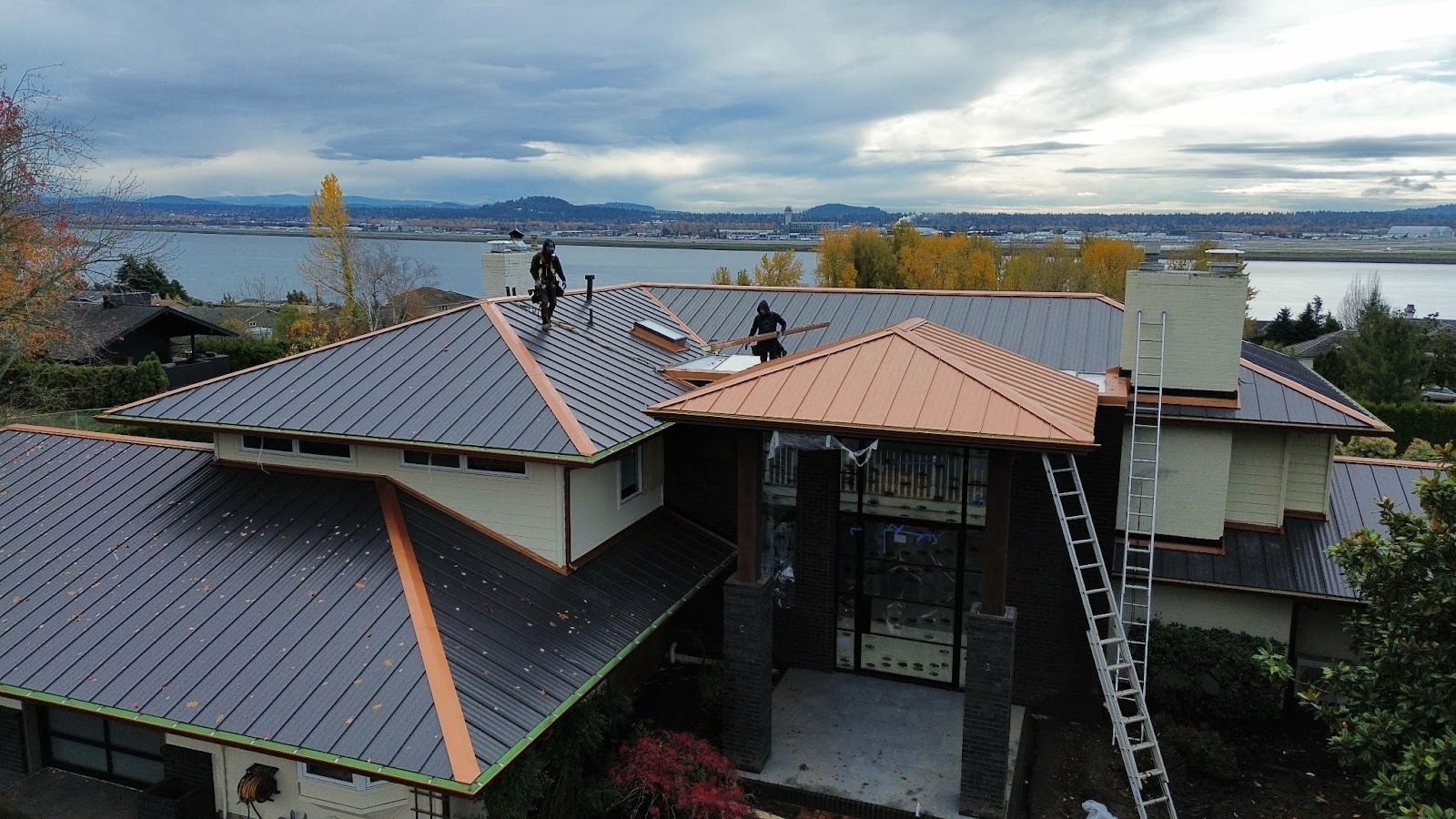 Metal roof installation in Yacolt WA showing workers installing standing seam metal panels on residential home