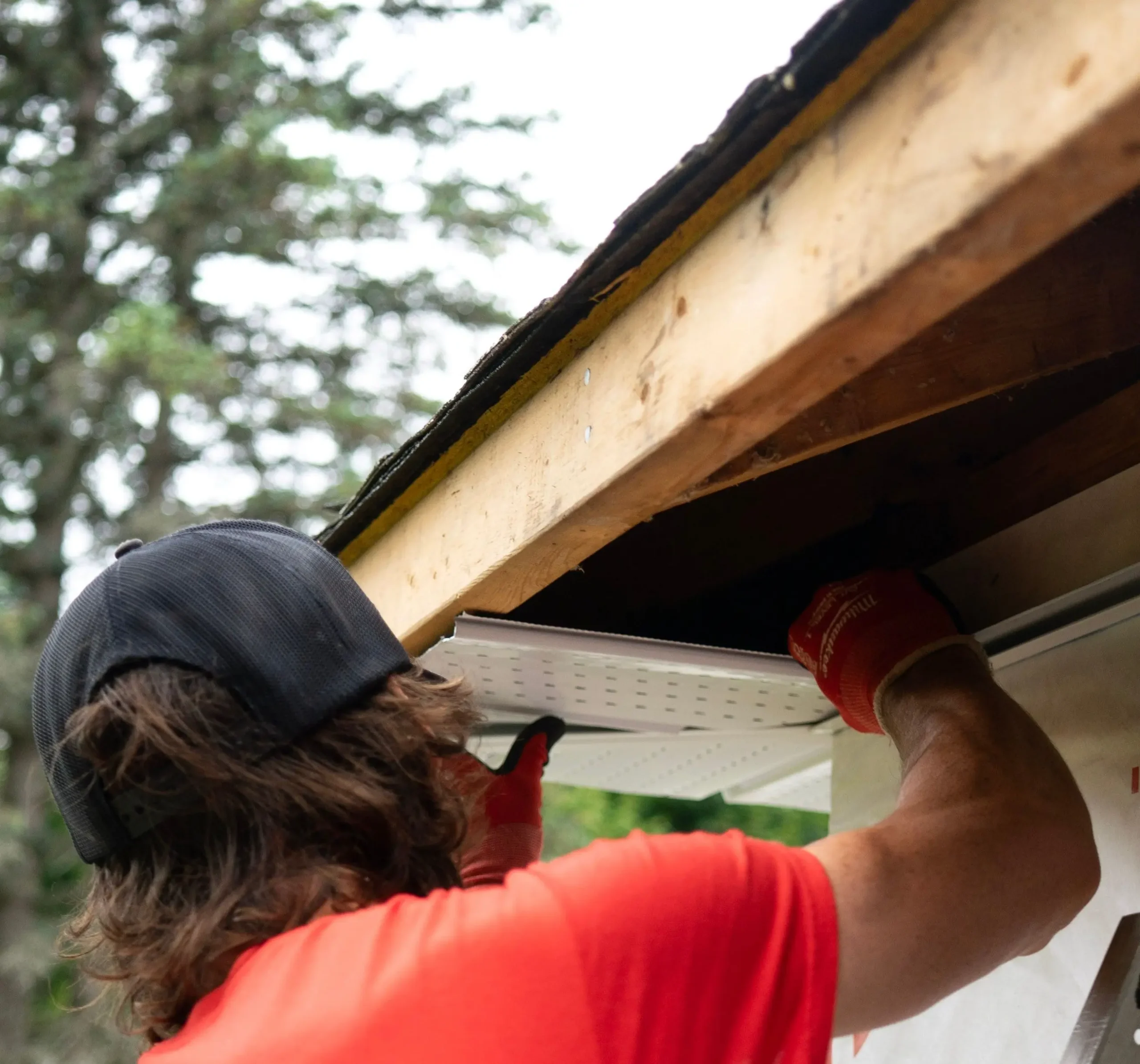 Roofing technician working along the roof edge during a gutter installation 