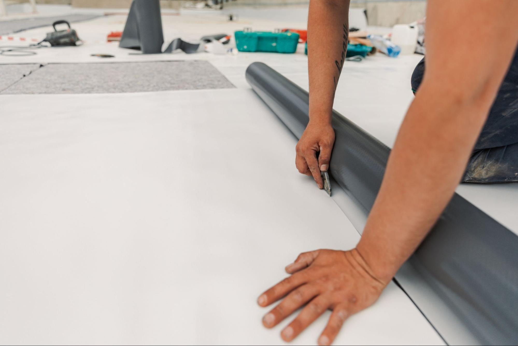 Roofer installing new membrane during a commercial roof replacement on a flat roof